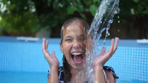 Dolce bambina si diverte in piscina spruzzando nell'acqua spruzzandola su lati diversi. Buona infanzia, vacanze estive — Video Stock