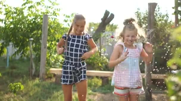 Dvě krásné školačky skáčou v zahradě, zatímco se rozhojí vodou. Školní prázdniny, odpočinek ve vesnici — Stock video