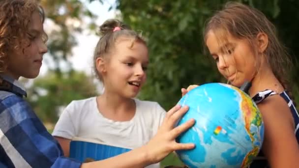 Studente della scuola elementare con mondo globo. I bambini comunicano con entusiasmo. Ritorno a scuola — Video Stock