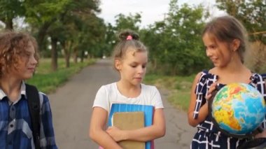 Okuldan dönerken üç çocuk gülüyor. Kız büyük bir küre taşıyor. Yine okul, mutlu çocuklar.