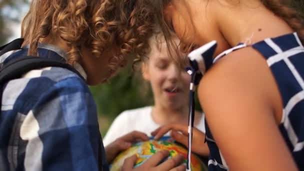 Primo piano di bambini che tengono in mano un globo molto grande. Tornati a scuola, i compagni studiano una mappa del mondo — Video Stock