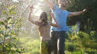 Kıvırcık saçlı çocuk babasını hortumla fışkırtıyor. Köyde tatil, babalar günü