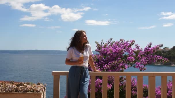Средиземноморский морской пейзаж с девушкой, смотрящей на море с красивой деревянной с цветами террасы с видом на море — стоковое видео