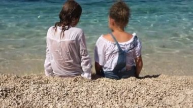 Isliç elbiseli erkek ve kız yüzme, yaz tatili, Hırvatistan'da tatil sonra deniz kıyısında oturuyor