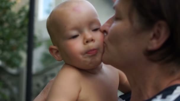 A avó feliz beija um neto. Um ano de idade bebê em seus braços avós, outdor retrato — Vídeo de Stock