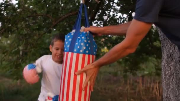 L'enfant frappe avec les mains sur les gants d'entraînement entraîneur instructeur. Entraînement de boxe avec un entraîneur en plein air. Développement du sport — Video