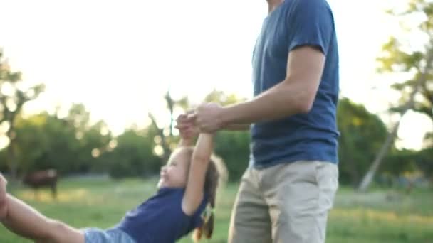 Мать и отец размахивают своей маленькой дочерью, держа его за руки и ноги. Счастливых семейных выходных, летних каникул — стоковое видео