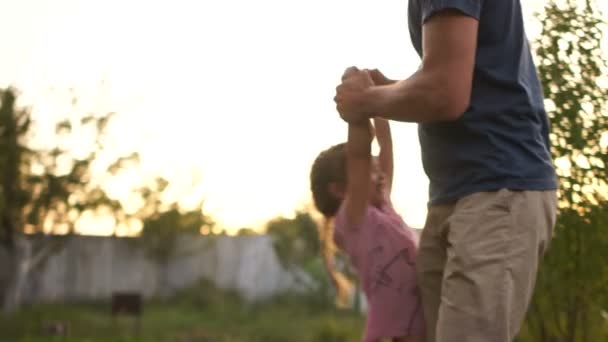 Ein glücklicher Vater im Park umkreist seine kleine Tochter, die ihre Hände hält. glückliche Kindheit, Vatertag, glücklicher Familienurlaub — Stockvideo