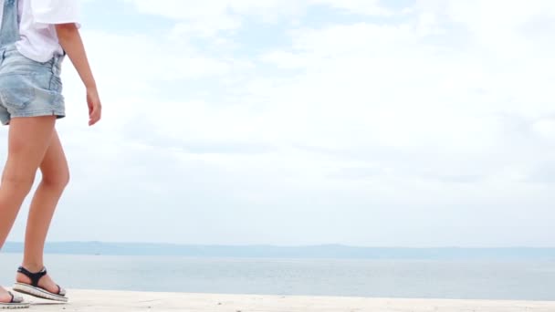 Niños felices juegan en el muelle del mar. Niño y niña vestidos con camisas blancas y jeans, vacaciones de verano, bromeando — Vídeos de Stock