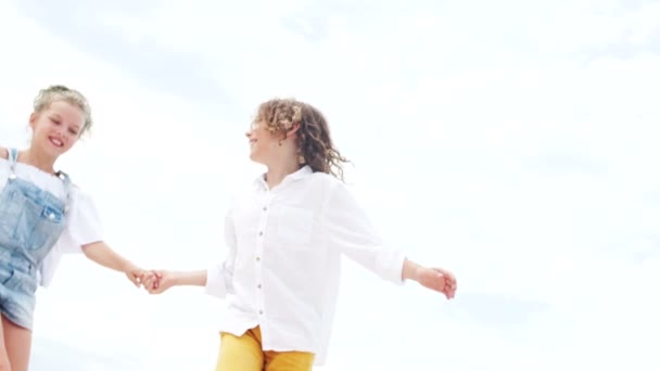 Kärleksfulla tonåringar tittar på varandra mot bakgrund av en solig sommarhimmel. Ljus denim, Happy Children, sommarlov — Stockvideo