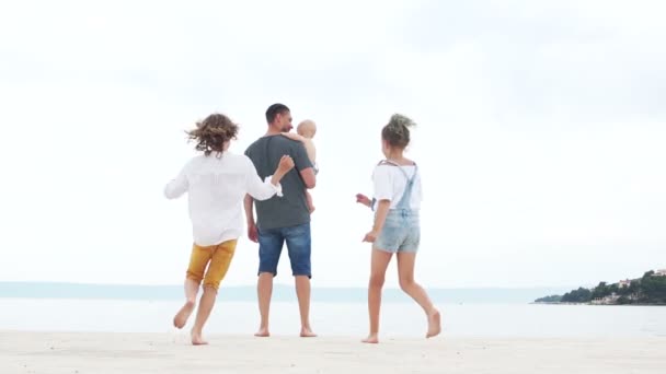 Young man with three children on the beach. The baby in the arms of his father and two teenagers, a boy and a girl. Lonely father, fathers day Stock Footage