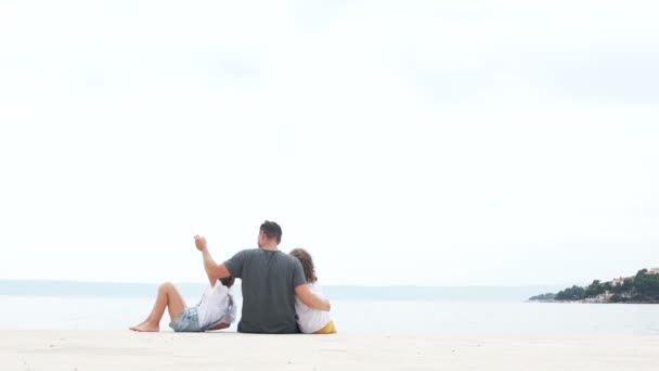 Батько і двоє його дітей, хлопчик і дівчинка, залишають пляж після відпочинку на білому піску, літні канікули — стокове відео