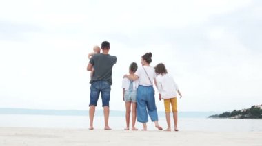 Aile gezisi. Ebeveynler ve kot pantolon giymiş üç çocuk deniz, yaz tatili tarafından beyaz kum üzerinde dinleniyor