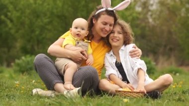 Güzel bir aile piknikte parkta kucaklıyor. Mutlu Paskalya ailesi. Annem ve iki oğlu. Anneler Günü