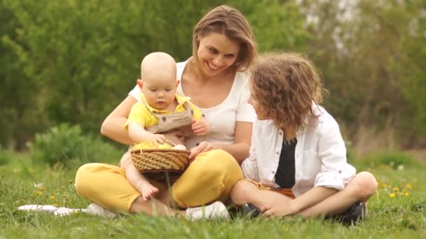 Pique-nique familial, maman avec deux fils. Le gamin examine les œufs de Pâques — Video