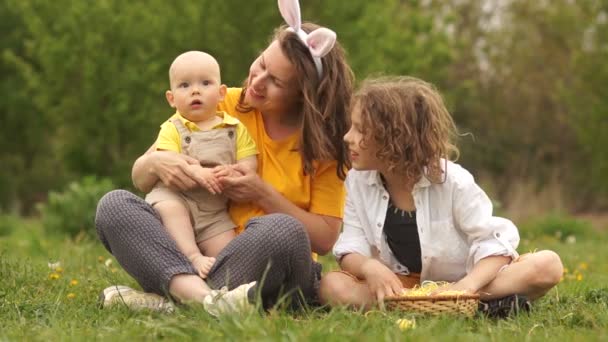 Mère et ses deux fils dans le parc lors d'un pique-nique. Week-end en famille, enfants et mère regardent au loin et rient — Video