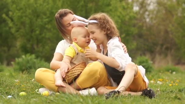 Härlig familj på påsk picknick, familjehelg. Barn med stor skillnad i ålder, mor och söner, barn når för sin äldre bror — Stockvideo