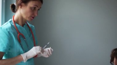 Doktor bebeğin annesinin kollarında oturmasını aşıladı. Ağlayan bebek, tıbbi manipülasyonlar, pediatri konsepti. Bağışıklık programı, grip aşısı. Yavaş çekim