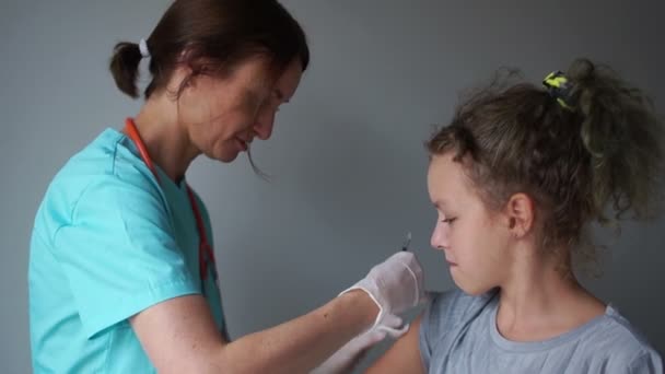 Sjuksköterska i kostym ger en influensaspruta till en tonårstjej i ett läkarrum. Influensavaccin, medicinsk manipulation — Stockvideo
