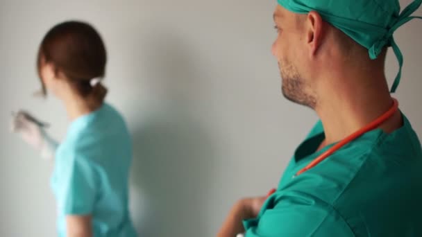 Doktorn och sköterskan överlägger i ett rum. Sjukvårdspersonal skrattar, medicinsk humor — Stockvideo
