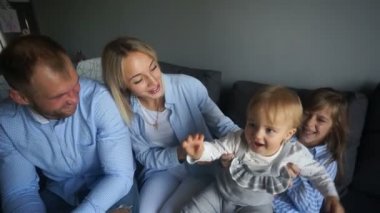 Hafta sonu evde eğlenen iki kızı olan mutlu bir aile. Ebeveynler ve çocuklar kot pantolon giyiyor.