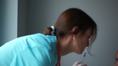 Kadın çocuk doktoru, annesinin kollarında oturan bebeğe grip aşısı yapıyor. Yakın plan. İnsülin enjeksiyonu, rutin aşılama