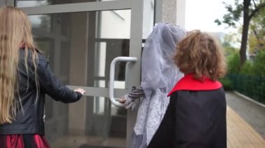 Çocuklar Cadılar Bayramı 'nı kutlar. Takım elbiseli ve makyajlı neşeli gençler komşulardan şeker istemek için evin girişine koşuyorlar.