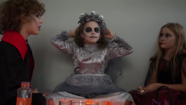 Девушка, одетая как мертвая невеста, собрала друзей на празднование Хэллоуина. Дети в костюмах и гриме смеются и разговаривают — стоковое видео