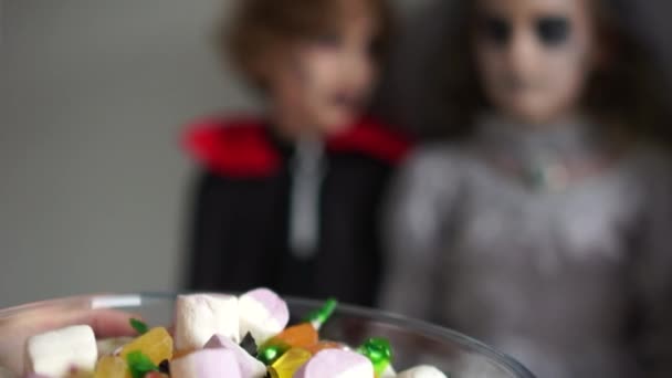 Primer plano de los niños en trajes y maquillaje para la fiesta de halloween estirar las manos a la cesta con dulces. Truco o trato — Vídeos de Stock