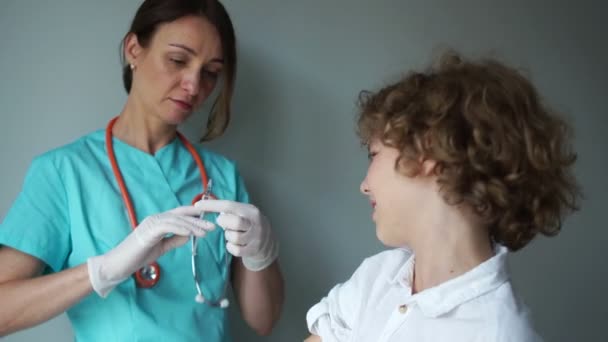 Вакцинация гриппа. Подростку делают прививку. Курчавая школьница и медсестра в медицинском кабинете — стоковое видео