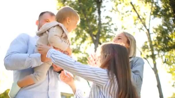 Två systrar och deras föräldrar har kul utomhus. Stor ung familj i parken för en promenad i solens strålar — Stockvideo