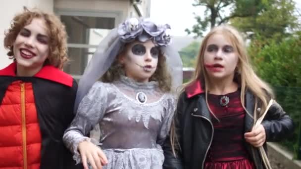 Todas las Reliquias Eve. Niños con disfraces y maquillaje de una novia muerta y un vampiro caminan por la calle celebrando Halloween — Vídeo de stock