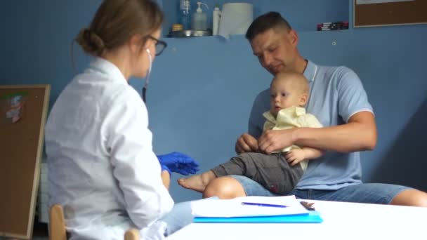 Молодий чоловік привів свого півторарічного сина до лікаря на обстеження педіатра. Педіатр робочого місця — стокове відео