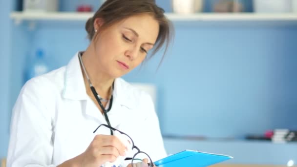 Dottore donna con un cappotto bianco e occhiali con una cartella in mano. Infermiera professionale, medicina e sanità — Video Stock