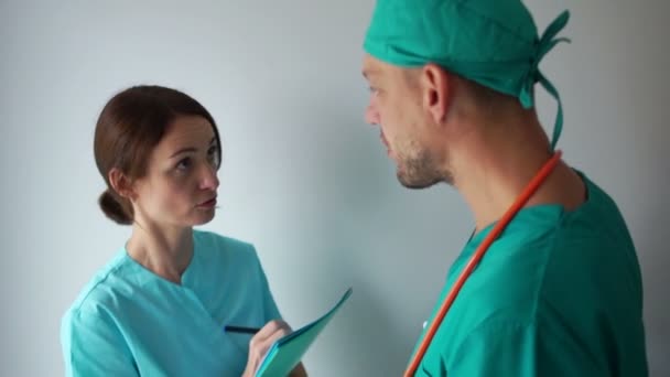 Медсестра и врач в больничной палате обсуждают режим лечения пациентов. Медицинский персонал клиники за работой — стоковое видео