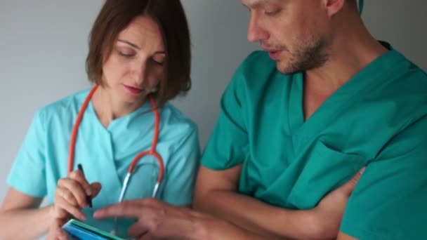 I colleghi medici discutono le questioni di lavoro nel tirocinio. Medici di sesso maschile e femminile in cappotti intermedici verdi — Video Stock