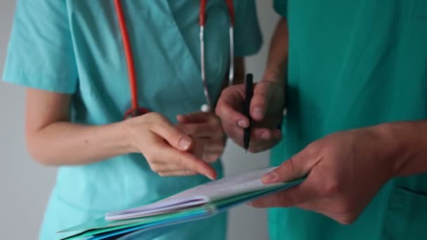 Los médicos discuten los resultados de los ensayos clínicos. Asistentes de laboratorio en el trabajo. Primer plano de la mano de los médicos, hombre y mujer con documentos médicos, plan de tratamiento, historial médico — Vídeo de stock