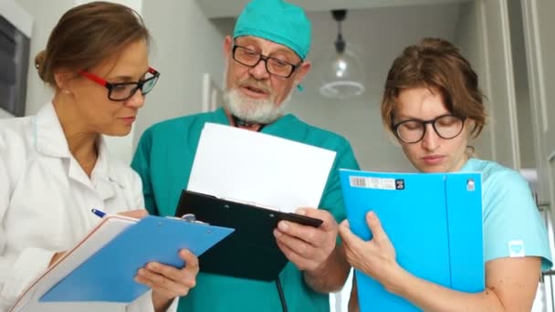 Pessoal médico da clínica a trabalhar. Médico cirurgião e duas de suas assistentes médicas jovens. Retrato de perto, medicina e conceito de saúde — Vídeo de Stock