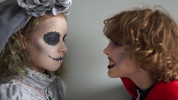 Roligt porträtt av två tonåringar i halloween kostymer och ljusa makeup. Barn grimasera och ha kul på Halloween. Närbild — Stockvideo