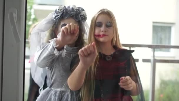 Close-up. Adolescentes em trajes de Halloween e maquiagem batem na porta. Uma mulher não identificável traz-lhes doces numa tigela. Celebração de Halloween — Vídeo de Stock