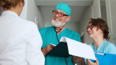 Klinik sağlık personeli iş başında. Meslektaşlar güler, tıbbi şakalar yapar. Tıp üniformalı üç doktor.