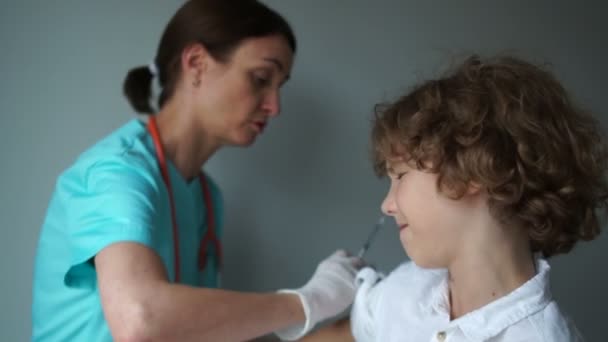 Asystentka medyczna szczepi kręconego chłopca. Szczepienie przeciw grypie, plan szczepień. Koncepcja medycyny i opieki zdrowotnej — Wideo stockowe