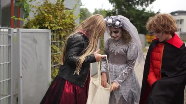 Tonåringar i kostym och smink Halloween samla godis från grannar. Halloween tradition, liv eller godis — Stockvideo