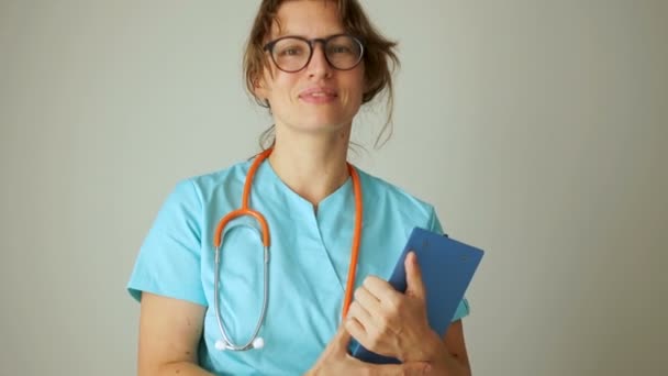 Médico pediatra mulher com um sorriso amigável olha para a moldura. Retrato de perto de um médico ou enfermeiro. Medicina e cuidados de saúde — Vídeo de Stock