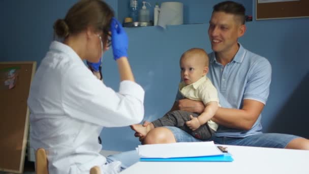 Beteg kisbaba az apjával az orvosi vizsgálaton a klinikán. Orvosi és egészségügyi gyermekgyógyászati koncepció — Stock videók