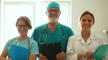 Klinikteki üç doktor pencerenin karşısında dururken gülümsüyor. Tıbbi personel, yakın portre.