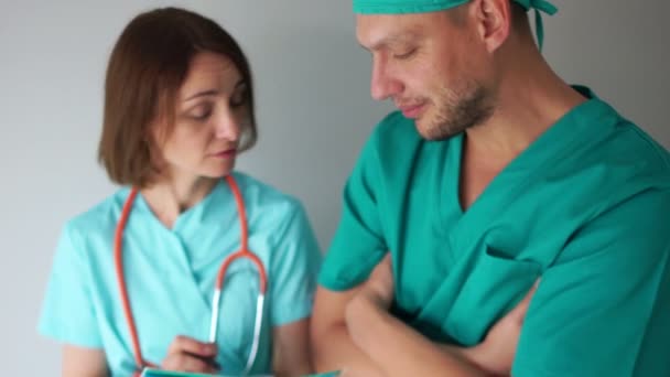 Personal médico durante el trabajo. Un hombre y una mujer con batas médicas verdes están discutiendo un plan de tratamiento para pacientes — Vídeo de stock