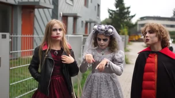 Прогулка по улице в страшных костюмах на Хэллоуин. Подростки идут праздновать Хэллоуин, День всех святых — стоковое видео