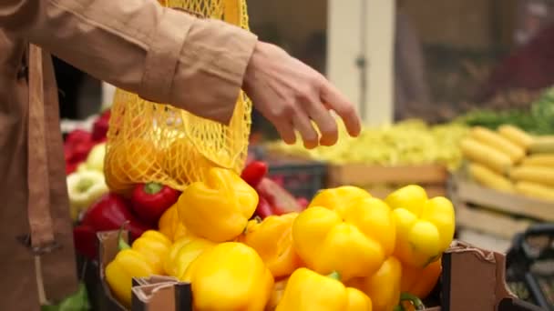 In Großaufnahme stapeln weibliche Hände gelben Pfeffer in einer Saitentüte. Öko-Verpackungen, Null Abfall, vegetarisches Essen — Stockvideo