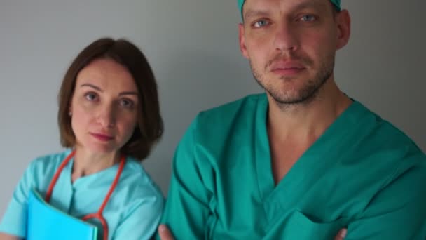 Homme et femme en robe médicale regardant la caméra et souriant. Médecine et santé, personnel médical de la clinique — Video